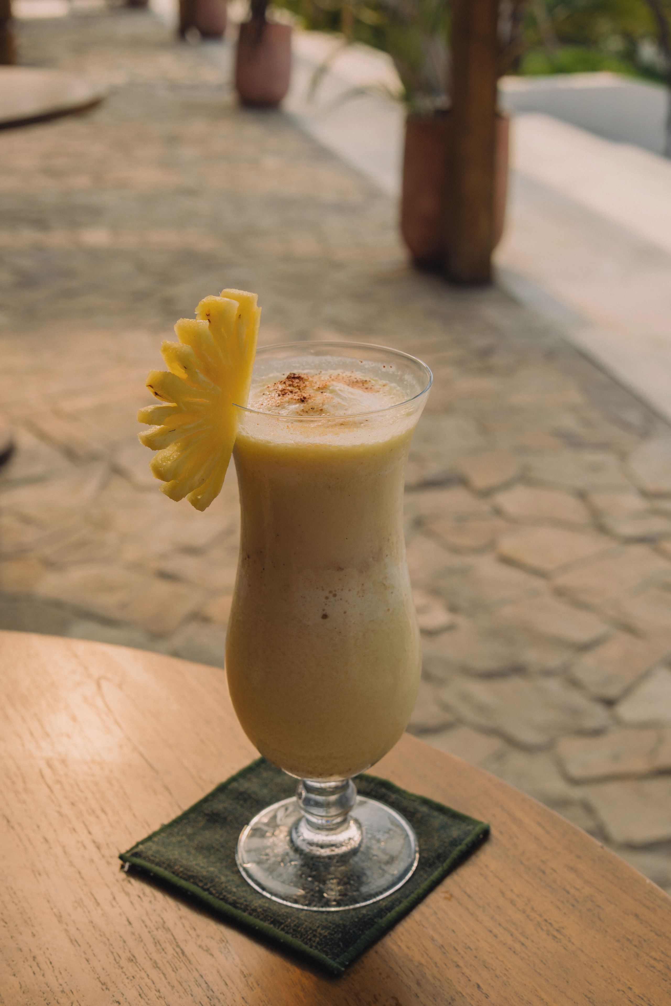 Ein Getränk im Glas mit einer Ananas-Garnitur auf einem Tisch.