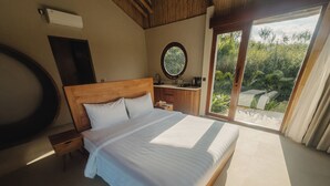 Un dormitorio con una cama grande, cabecera de madera, una mesita de noche, un espejo y vista a zonas verdes a través de una puerta corrediza.