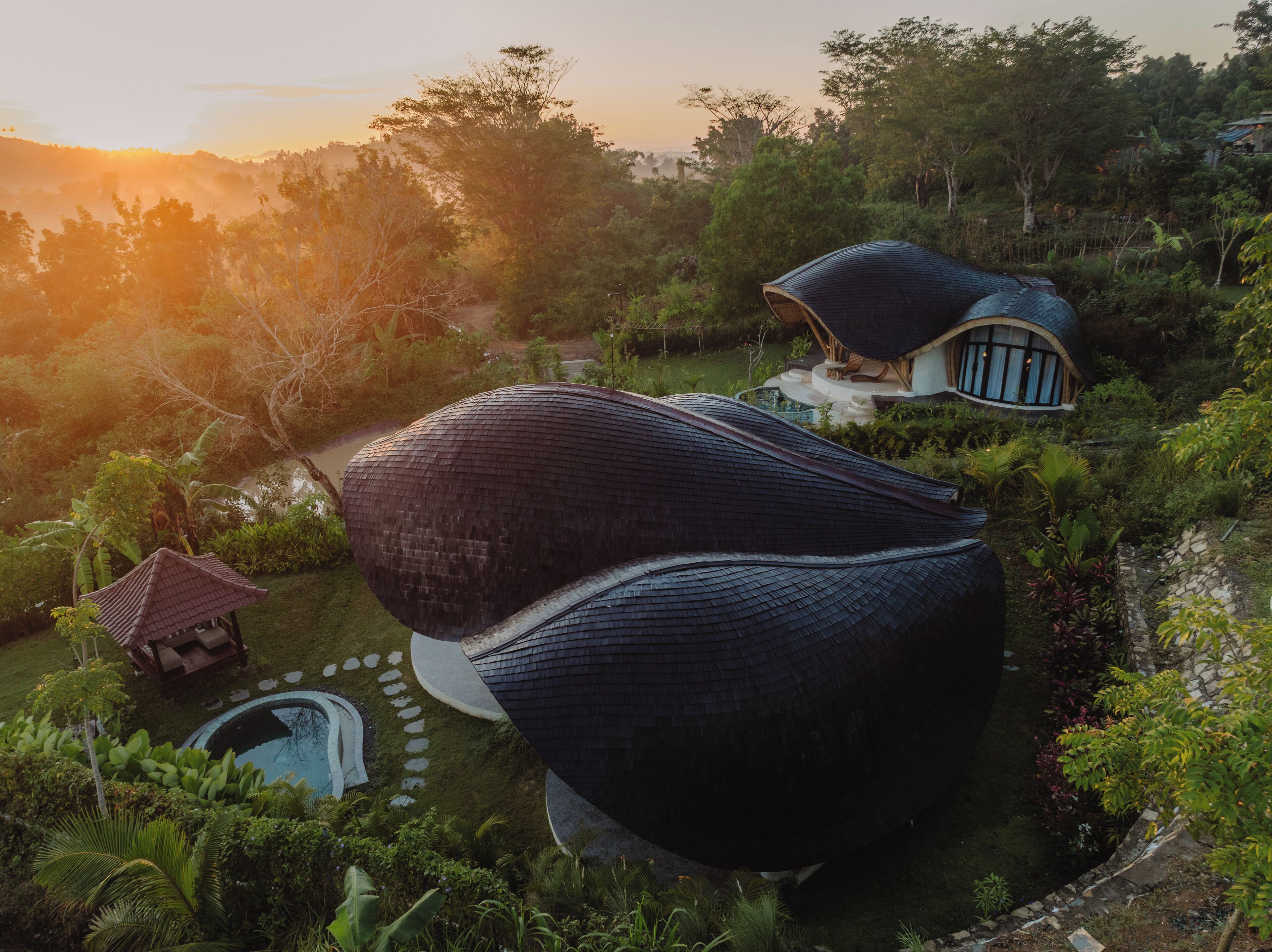 A unique, dome-shaped building surrounded by lush greenery and a small pond.