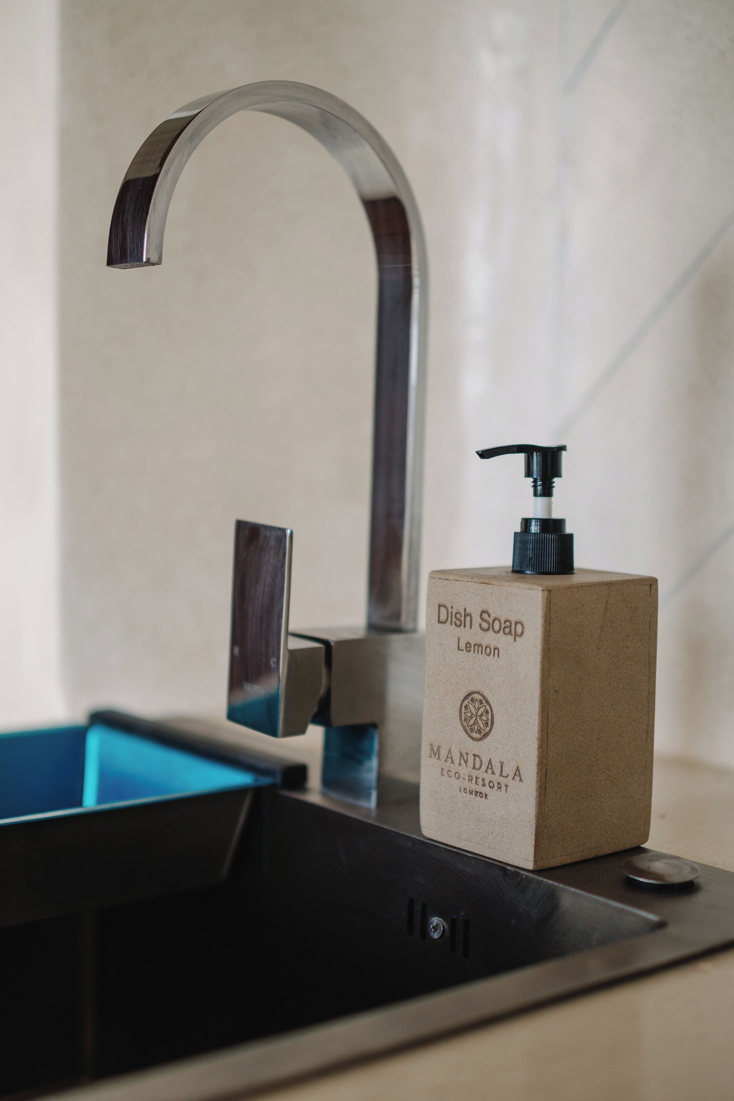 A kitchen sink with a modern faucet, a soap dispenser, and a blue countertop.