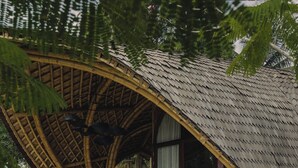 Zona junto a la piscina con estructura de bambú, asientos y una mesa.