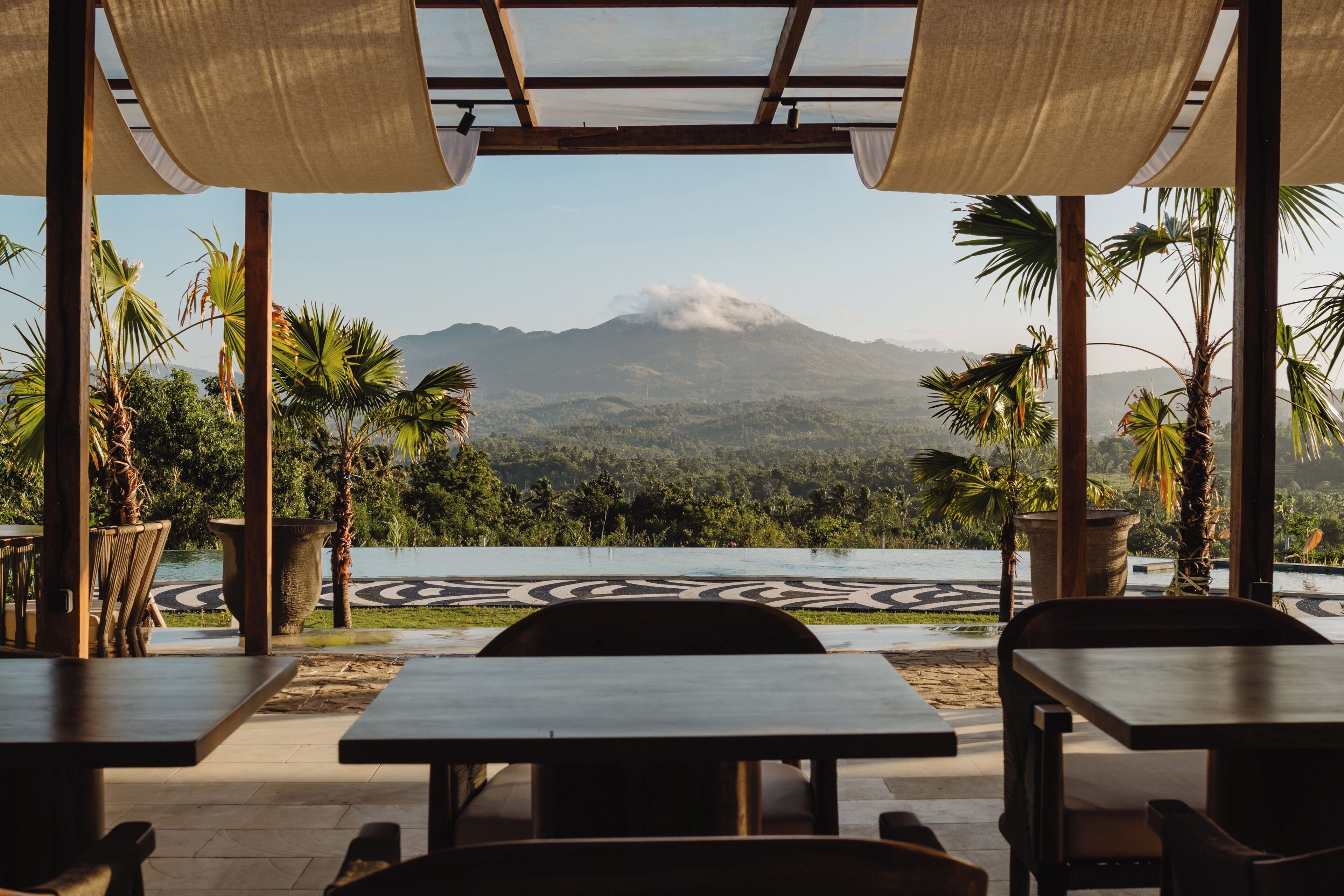 A restaurant with outdoor seating overlooking a mountain.