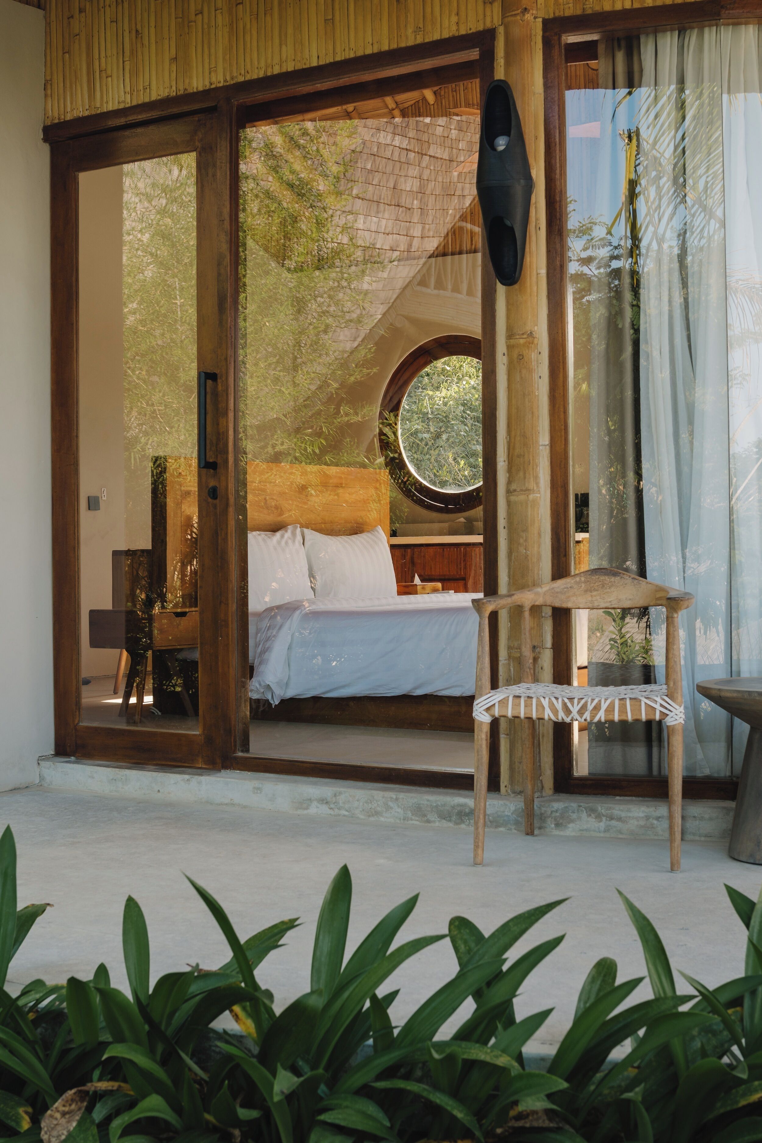 Un dormitorio con cama, una silla y un ventanal grande.