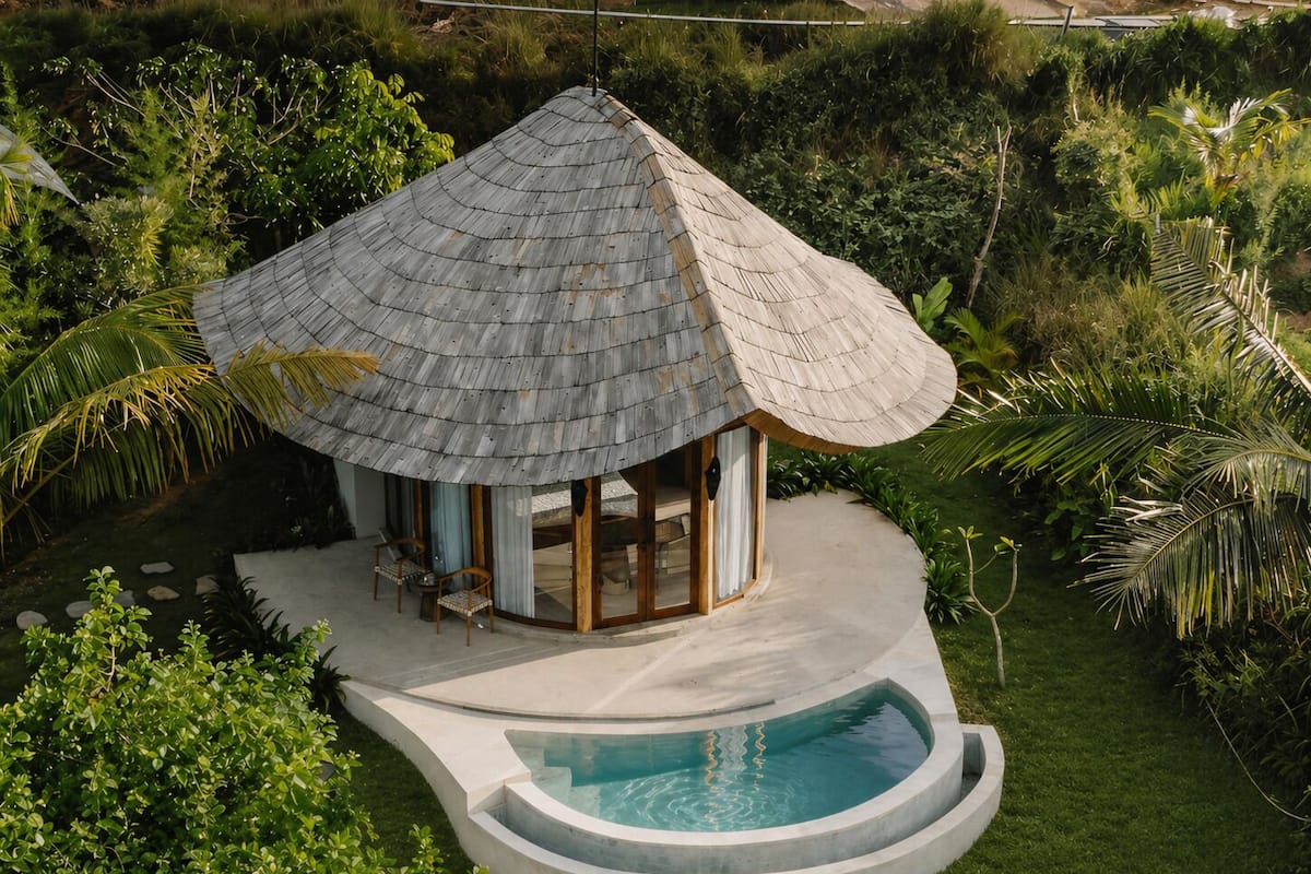 A thatched-roof structure with a pool, surrounded by lush greenery.