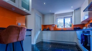A modern kitchen with white cabinets, a black tiled floor, and a window providing natural light. - 10 Guests - 5 Bedrooms - Free Parking - Lux House (Milton Keynes)