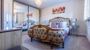 A bedroom with a large mirror, a tufted bed, and a chandelier. - 10 Guests - 5 Bedrooms - Free Parking - Lux House (Milton Keynes)