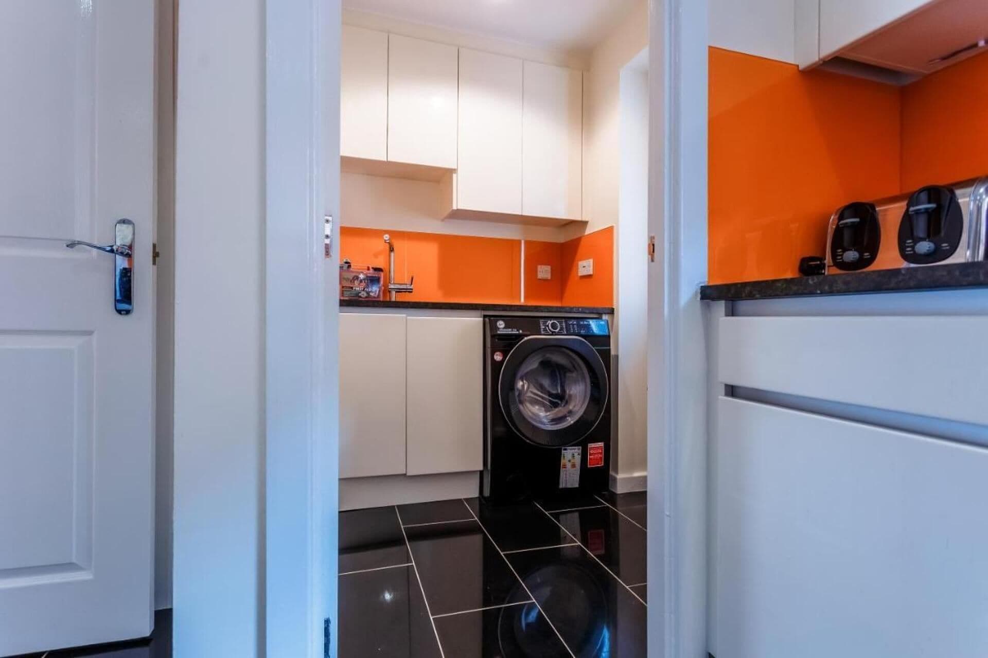 Eine kleine Küche mit Waschmaschine, Kaffeemaschine und Mikrowelle.