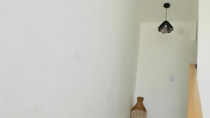 A wooden staircase with a white wall and a hanging light fixture.