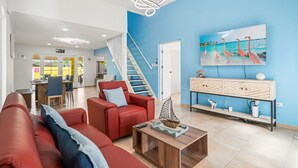 A modern living room with a red sofa, a wooden coffee table, and a blue wall. - Wayaca 231 (Oranjestad)