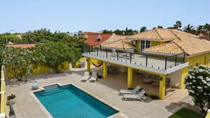 A two-story house with a swimming pool, outdoor seating, and a red-tiled roof. - Wayaca 231 (Oranjestad)