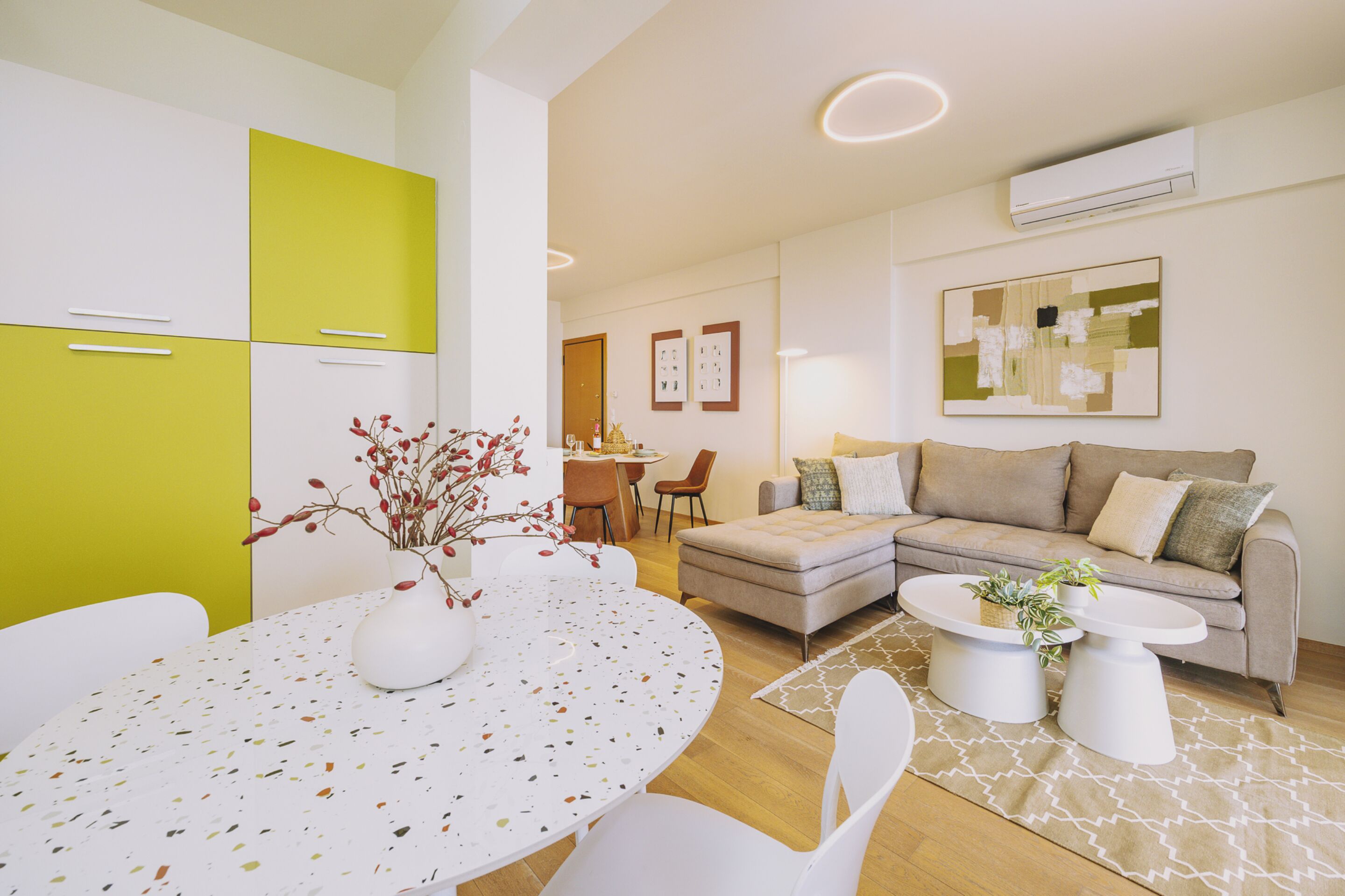 A modern living room with a round table, a sofa, and a dining area.