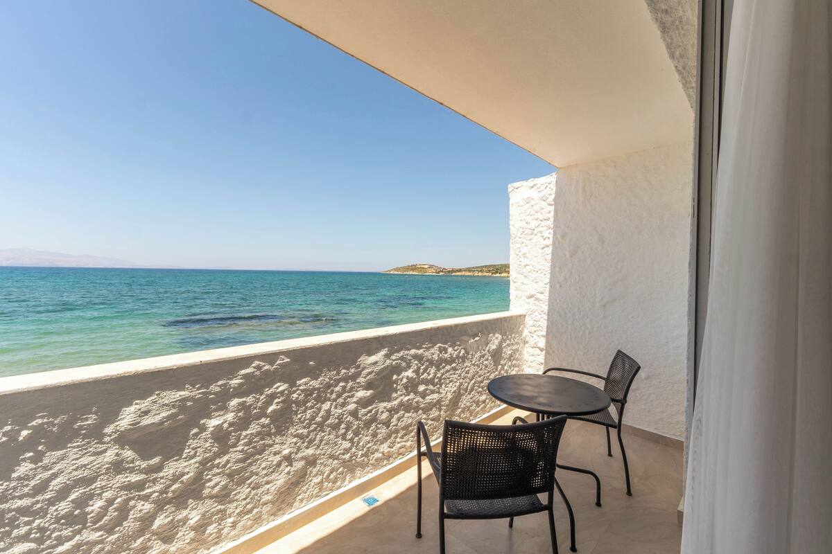 Un balcon avec vue sur la mer, une table et deux chaises.