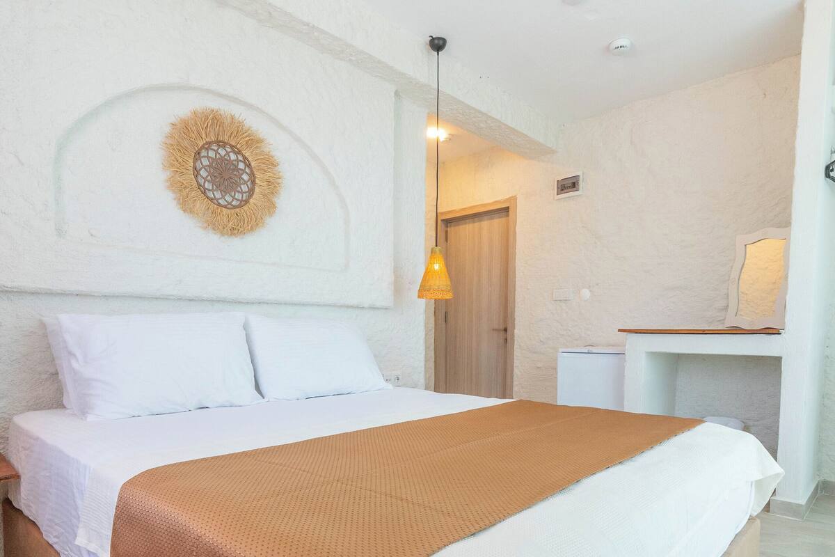 Une chambre à coucher comprenant un lit, une table de chevet, une lampe et une œuvre d’art accrochée au mur.