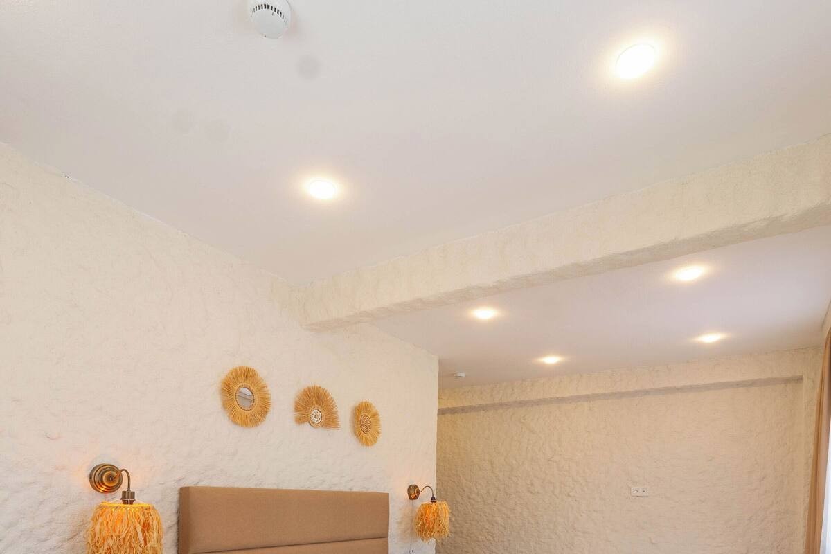 Une chambre d’hôtel avec un grand lit, un lit plus petit, une table de chevet et une lampe fixée au mur.