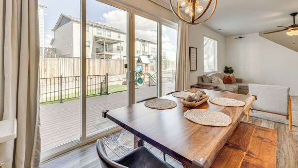 A spacious living area with a large wooden table, a ceiling fan, and a view of a backyard through sliding glass doors. - Bright Colorado Springs Home, 10 Mi to Dtwn! (Colorado Springs)
