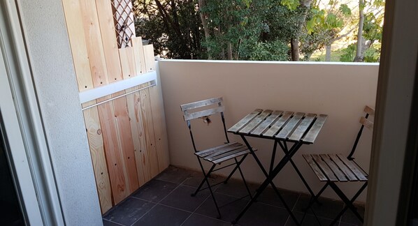 A small outdoor patio with a wooden fence, a metal table, and two chairs.