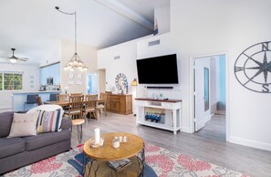 A modern living room with a sofa, dining table, and TV. - Mariners Club Unit 904, VRNR Luxury Collection, Brand New Completely Remodeled (Key Largo)