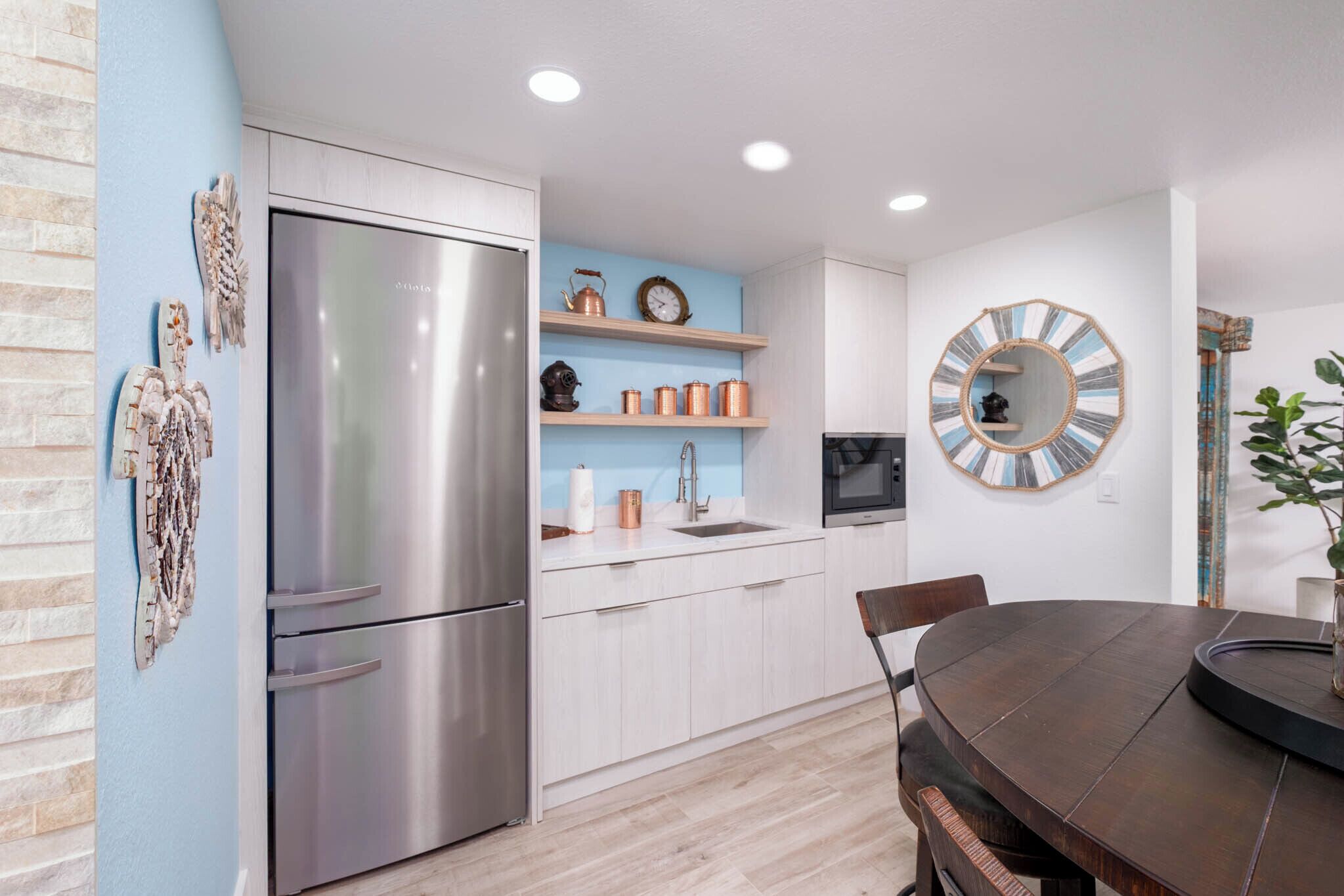 Una cocina moderna con un refrigerador de acero inoxidable, armarios blancos y una pared de acento azul.
