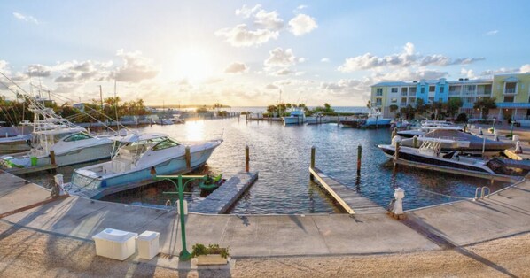 A marina with boats docked, a clear sky, and buildings in the background. - Mariners Club Unit 904, VRNR Luxury Collection, Brand New Completely Remodeled (Key Largo)