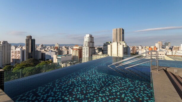 A rooftop infinity pool with a cityscape view, surrounded by high-rise buildings. - London SP Residences (Sao Paulo)