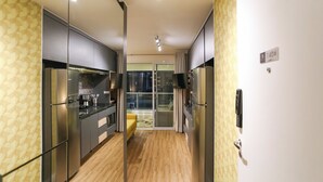 A modern kitchen with stainless steel appliances, a yellow patterned wall, and a sliding glass door leading to a balcony. - London SP Residences (Sao Paulo)