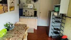A compact kitchen with a sink, fan, and small refrigerator.