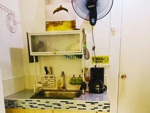 A compact kitchenette with a microwave, sink, and coffee maker. - Amigas Transient House (Santo Tomas)