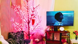A cozy living room with a television, a teddy bear, a Christmas tree, and a bookshelf.