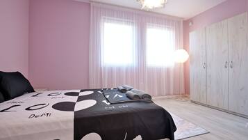 A bedroom with a bed, a wardrobe, and a window with curtains.