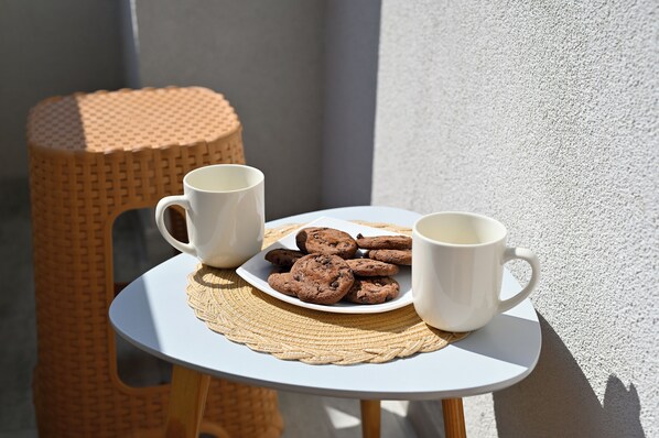 A small round table with a white plate of cookies and two white mugs.