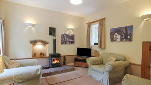 A cozy living room with a fireplace, comfortable seating, and wall-mounted lighting.