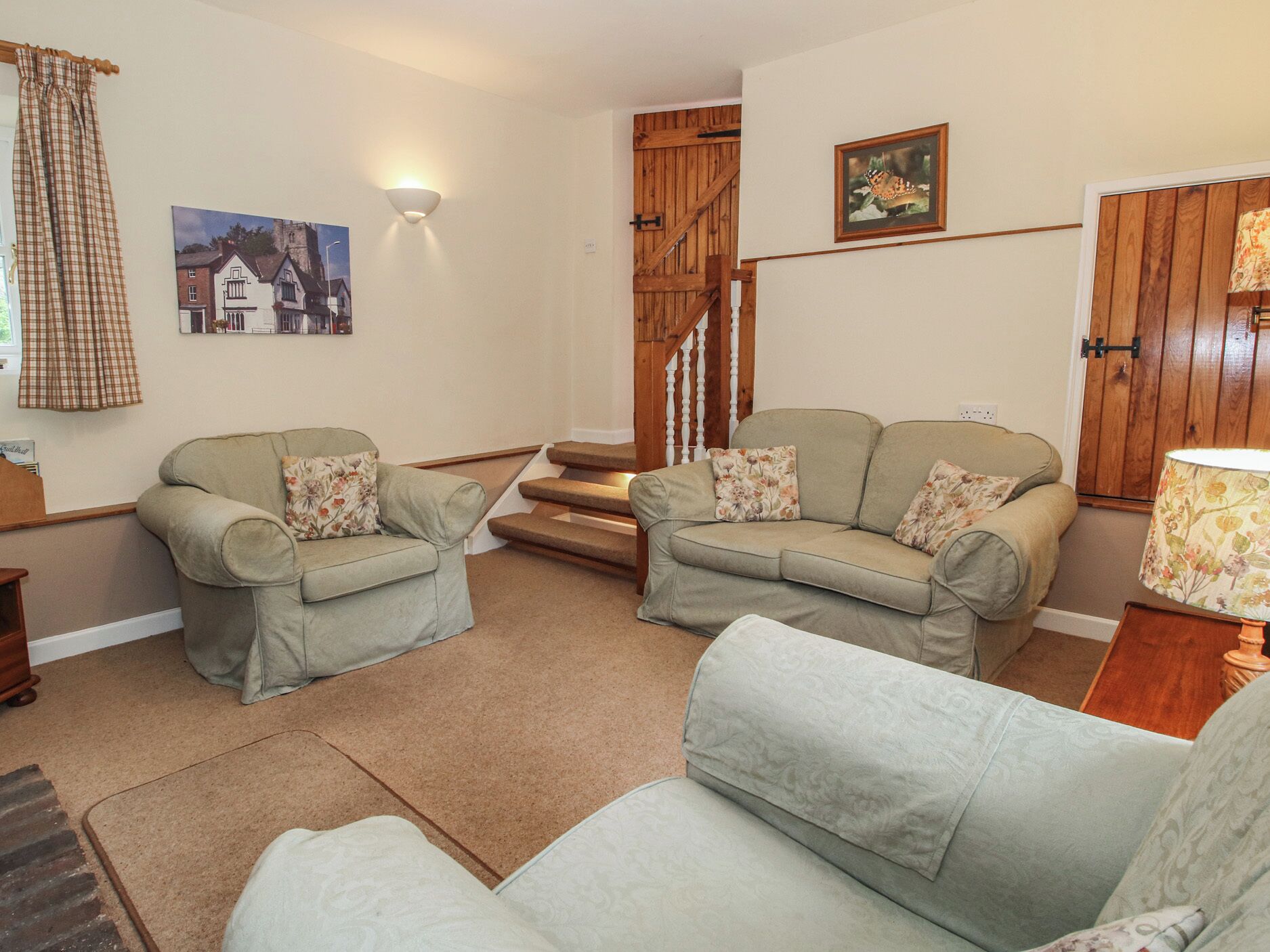 A cozy living room with two sofas, a staircase, and a wooden door.