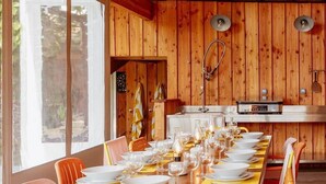 Een houten eethoek met een lange tafel voor zes personen, omringd door rieten stoelen.