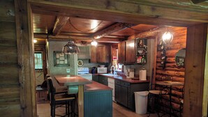 A rustic kitchen with wooden cabinets, a central island, a sink, and a stove. - Charming Cozy 2-bedroom cabin with WiFi, in enchanting Canyon Lake on the River (Canyon Lake)
