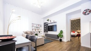 Ein modernes Wohnzimmer mit Essbereich, Holzboden und einem an der Wand befestigten Fernseher.