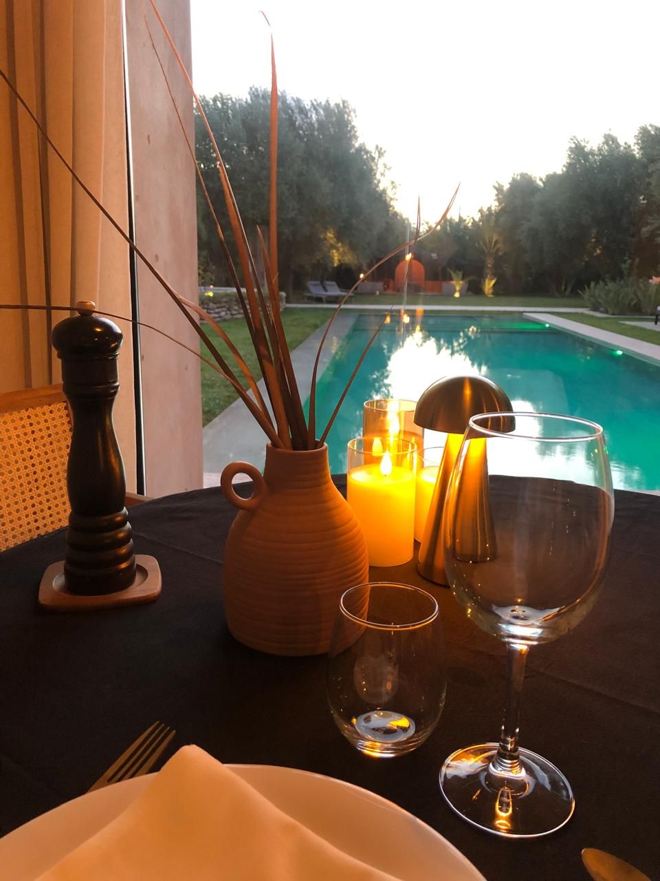 A dining table with a candle, a wine glass, and a salt and pepper shaker.