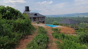 A house with a swimming pool, surrounded by greenery and hills. - Hillbilly Bush Lodge  (Kisumu)