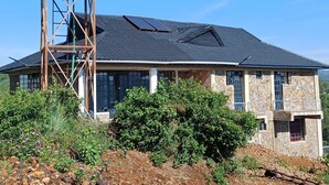 A house with a stone facade, large windows, and a solar water tank. - Hillbilly Bush Lodge  (Kisumu)