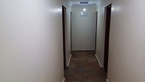 A narrow hallway with white walls and a stone floor. - Hillbilly Bush Lodge  (Kisumu)