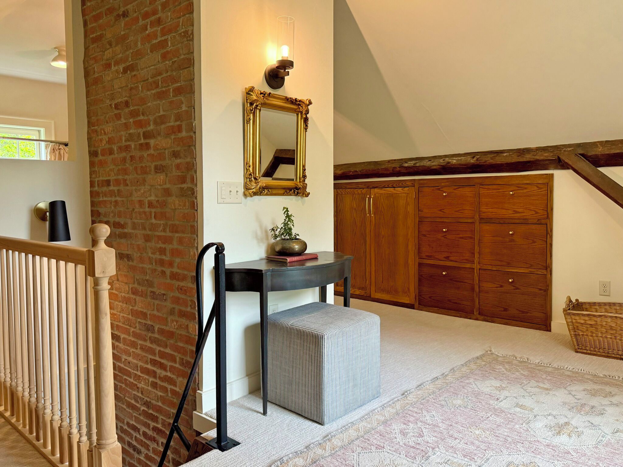 A staircase with a wooden handrail, a black wall-mounted light, a mirror with an ornate frame, and a wooden wardrobe with multiple doors.