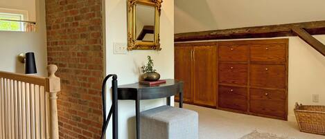A staircase with a wooden handrail, a black wall-mounted light, a mirror with an ornate frame, and a wooden wardrobe with multiple doors.