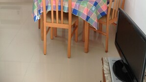 A dining area with a table covered by a colorful checkered tablecloth, surrounded by wooden chairs.