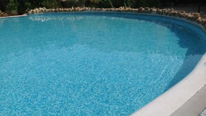 A clear blue swimming pool with a tiled edge and a stone border.