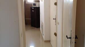 A hallway leading to a room with a white door, a microwave, and a cabinet.