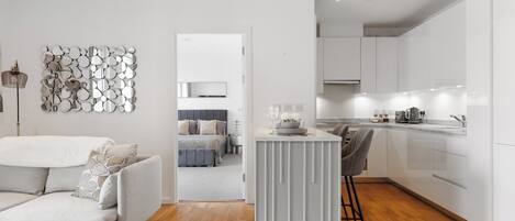 Une cuisine moderne avec des meubles blancs, un îlot central et un tabouret de bar.