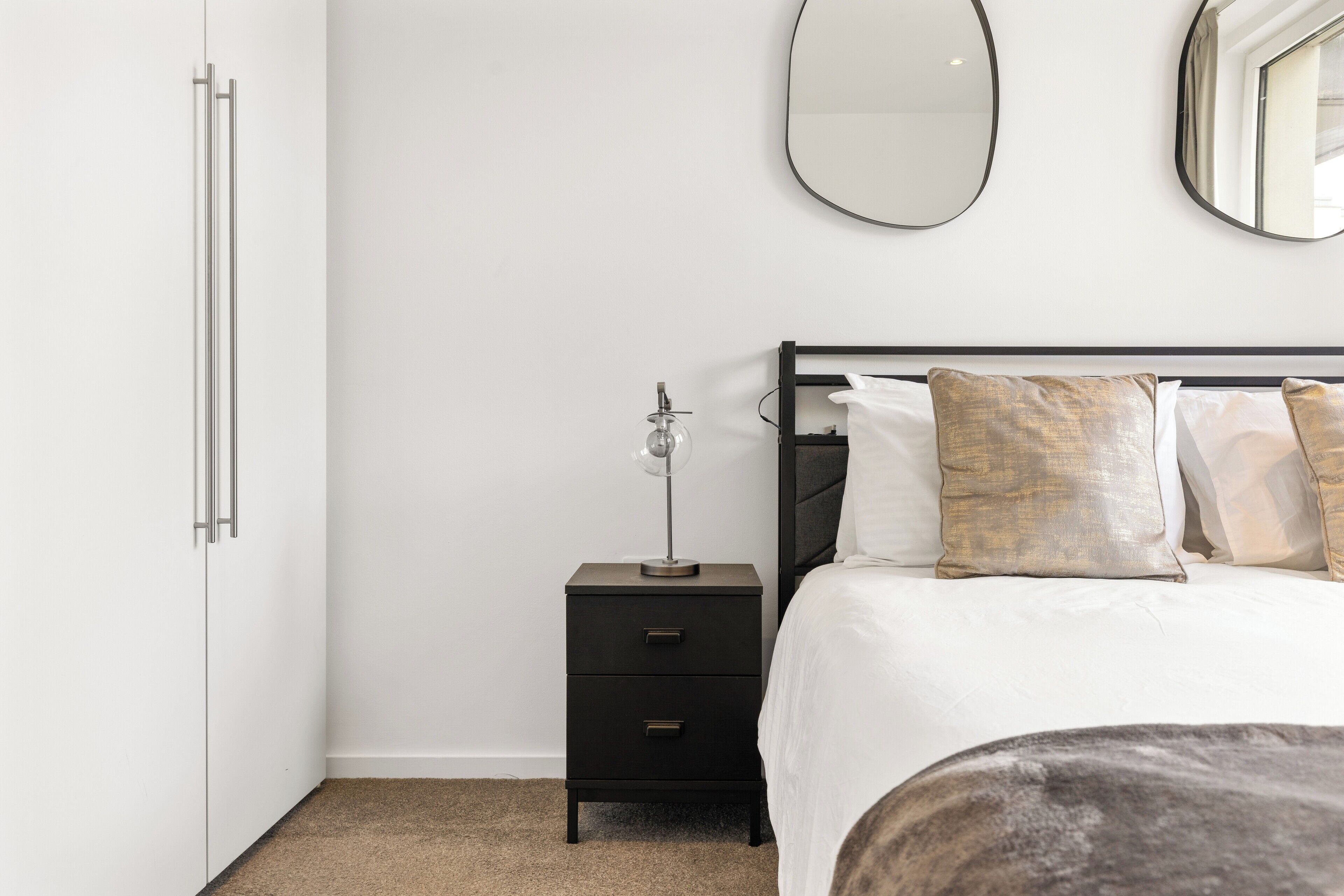 Una camera da letto con un letto, un comodino, uno specchio e un armadio.