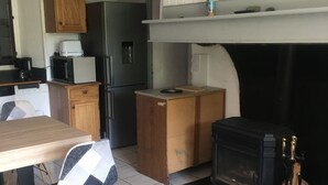 A compact kitchen with a built-in stove, wooden cabinets, and a dining area with a table and chairs.