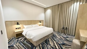 Une chambre d’hôtel avec un grand lit, une table de chevet avec une lampe, une chaise et un bureau.
