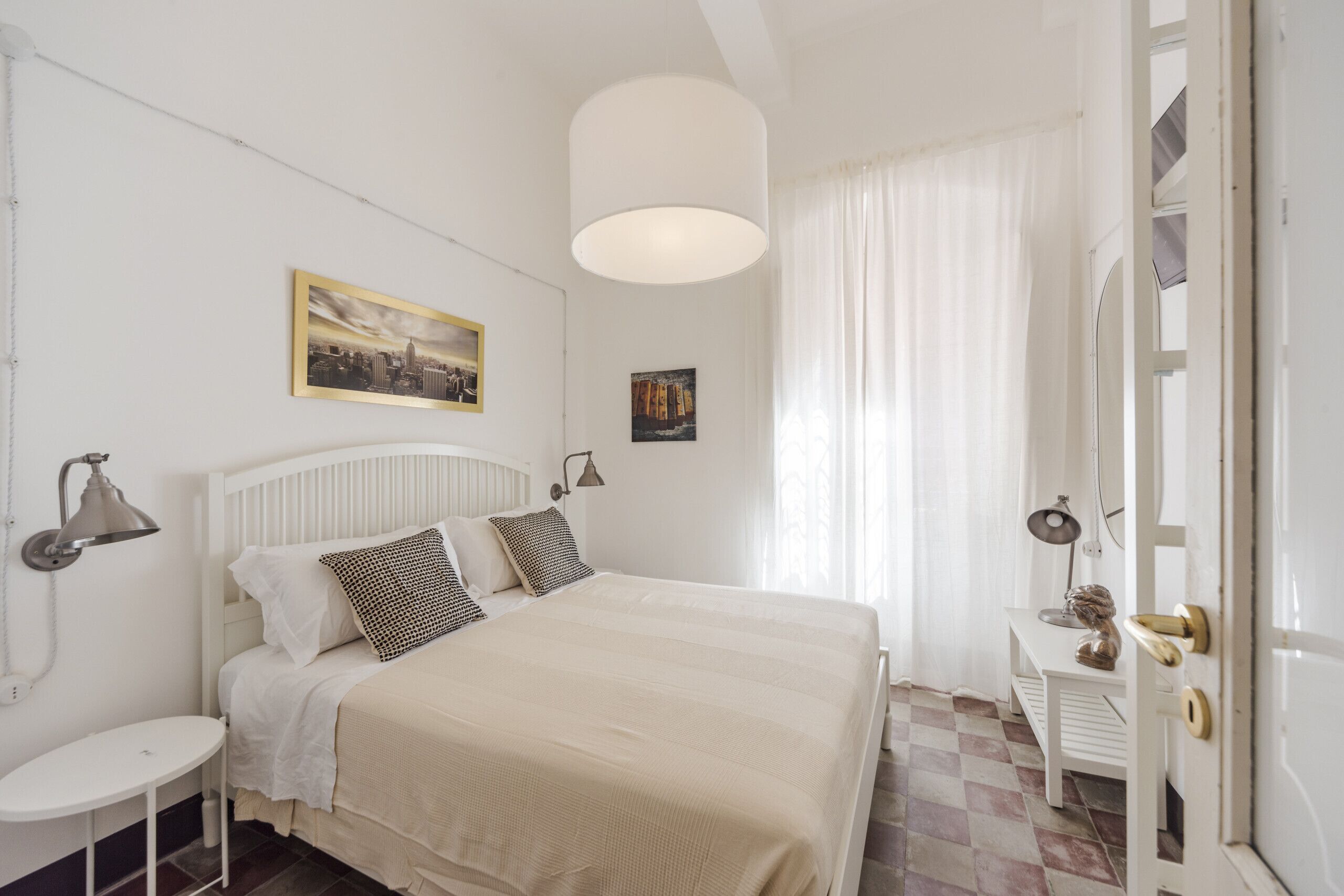 A bedroom with a bed, bedside tables, a lamp, and a door with a brass handle.