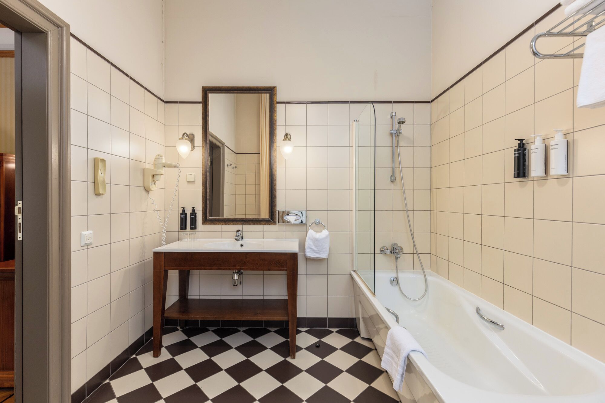 A bathroom with a checkered floor, a sink, a mirror, a shower, and a bathtub.
